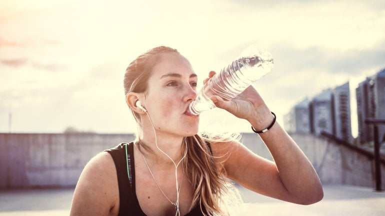 eine Frau trinkt beim Sport aus einer Flasche mit Leitungswasser