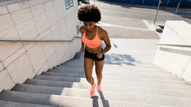 Eine Frau in kurzer Hose und Sport-BH läuft eine Treppe hoch.